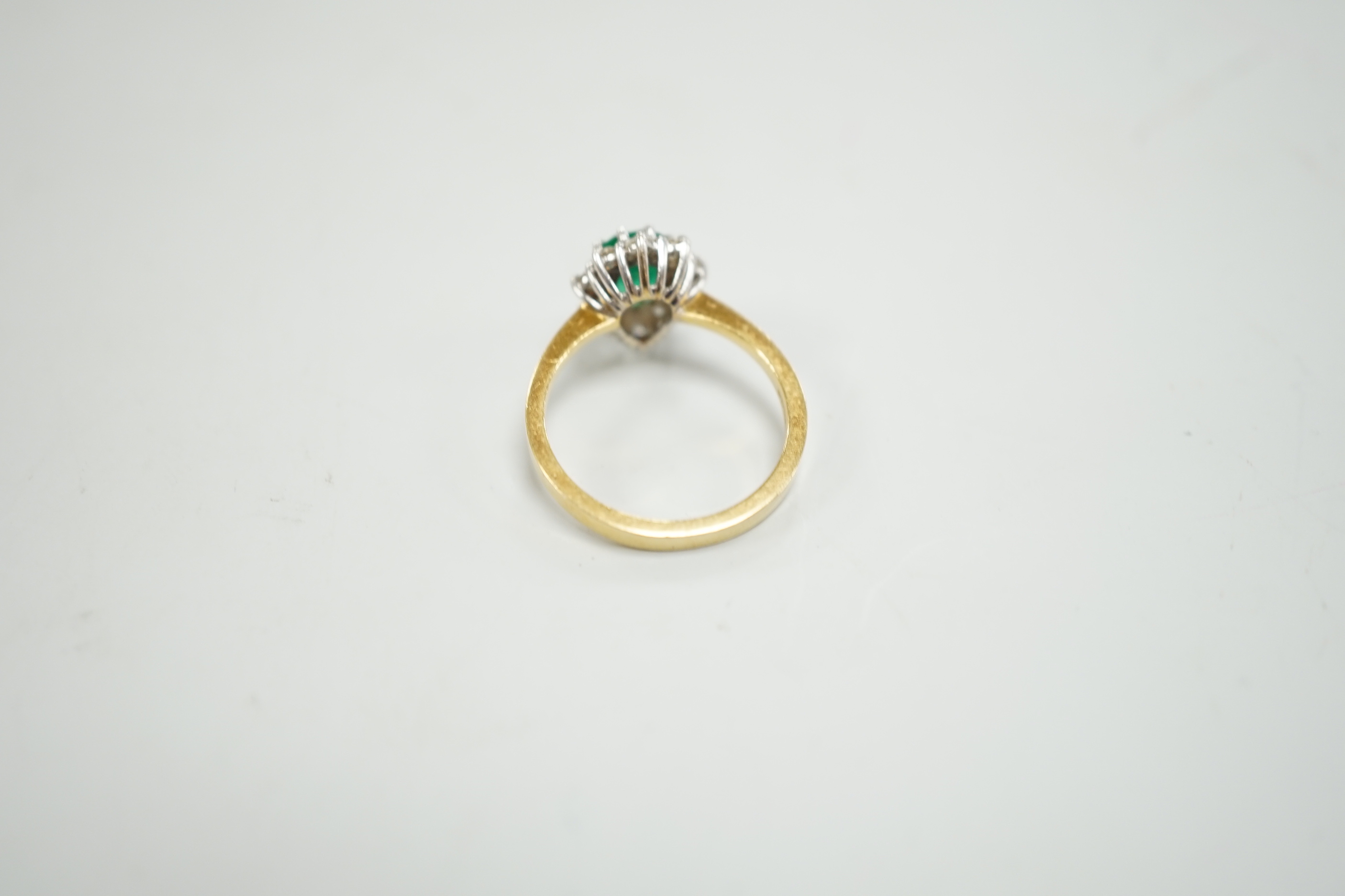 A modern 18ct gold, single stone emerald and diamond chip set pear shaped cluster ring, size M/N, gross weight 3.9 grams.